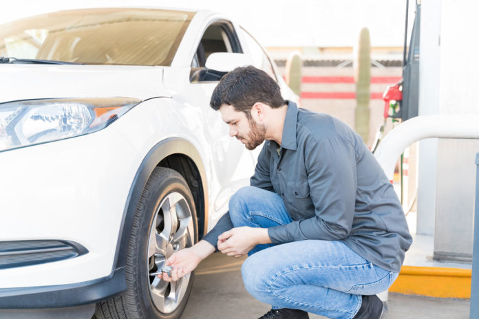 Repairman Checking Air Pressure At Gas Station