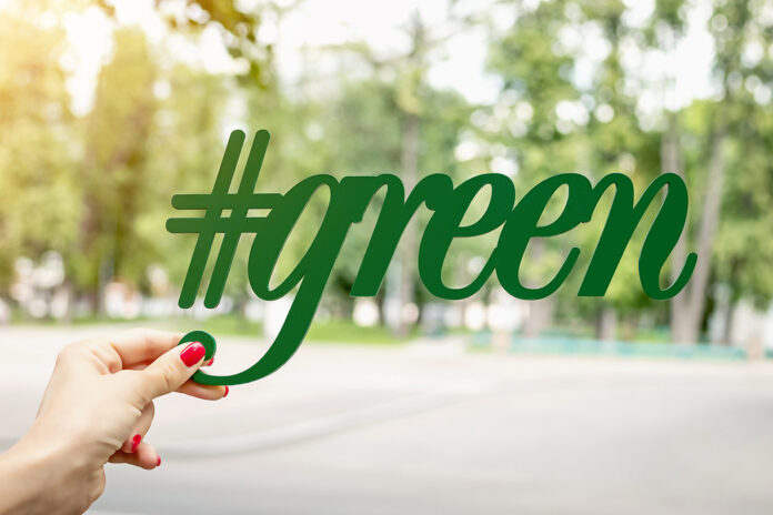 Green letters in woman hand in the park, green background. City background, alphabet, organic.