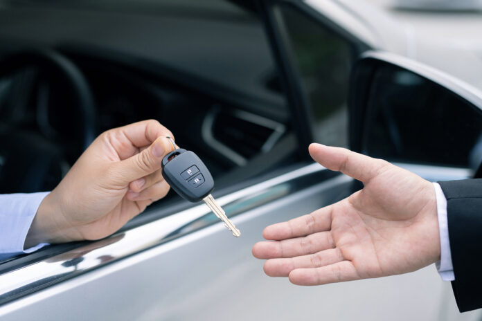 The salesman holds the new car keys. Ready to deliver to customers at the showroom.