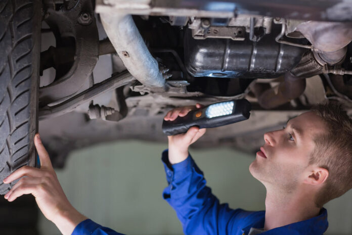 Young mechanic examining car